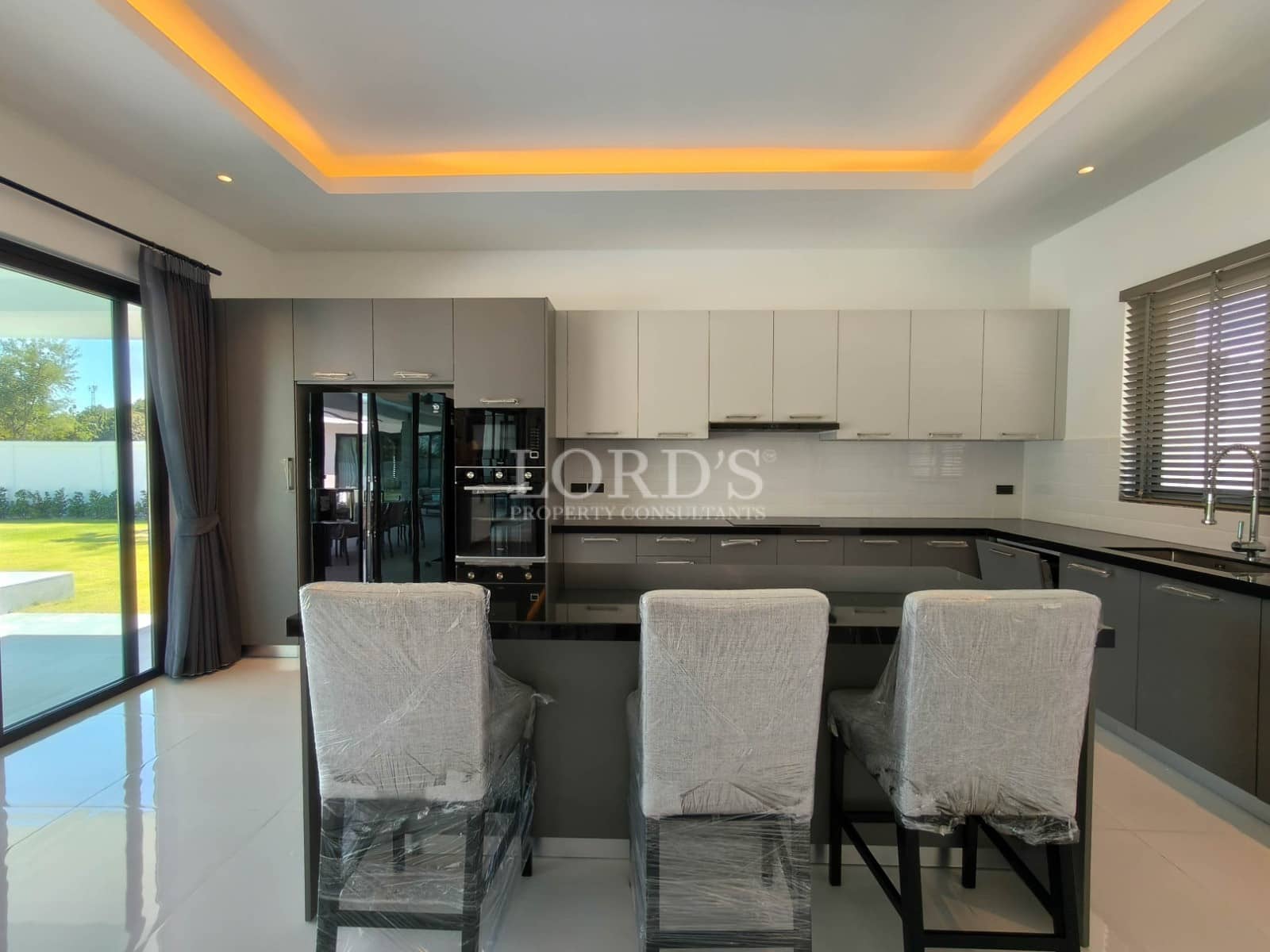 Modern kitchen with breakfast bar seating, built-in appliances, ambient ceiling lighting, and sleek cabinetry.