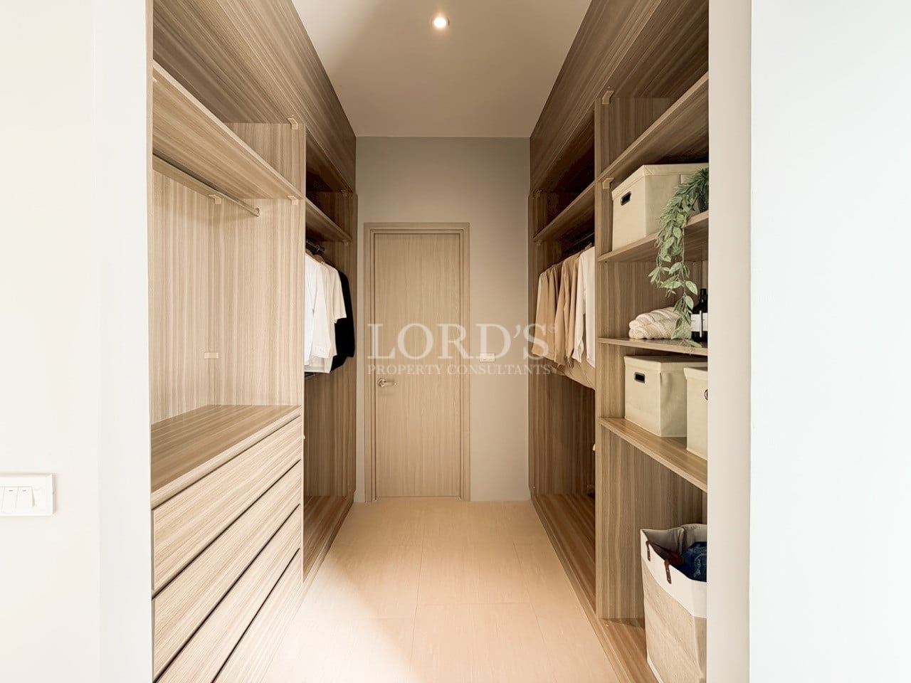 Walk-in closet with custom wooden shelving, hanging space, drawers, and soft ambient lighting.