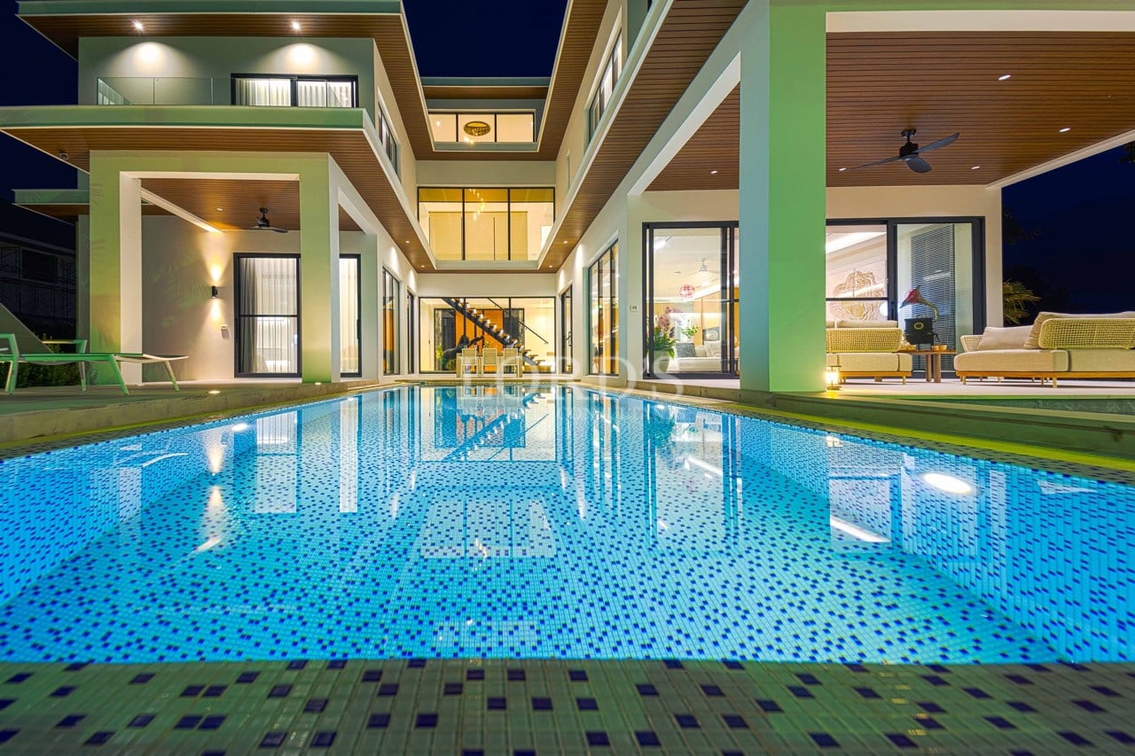 Nachtansicht einer modernen Luxusvilla mit beleuchtetem Swimmingpool und offenem Innenhofdesign.
