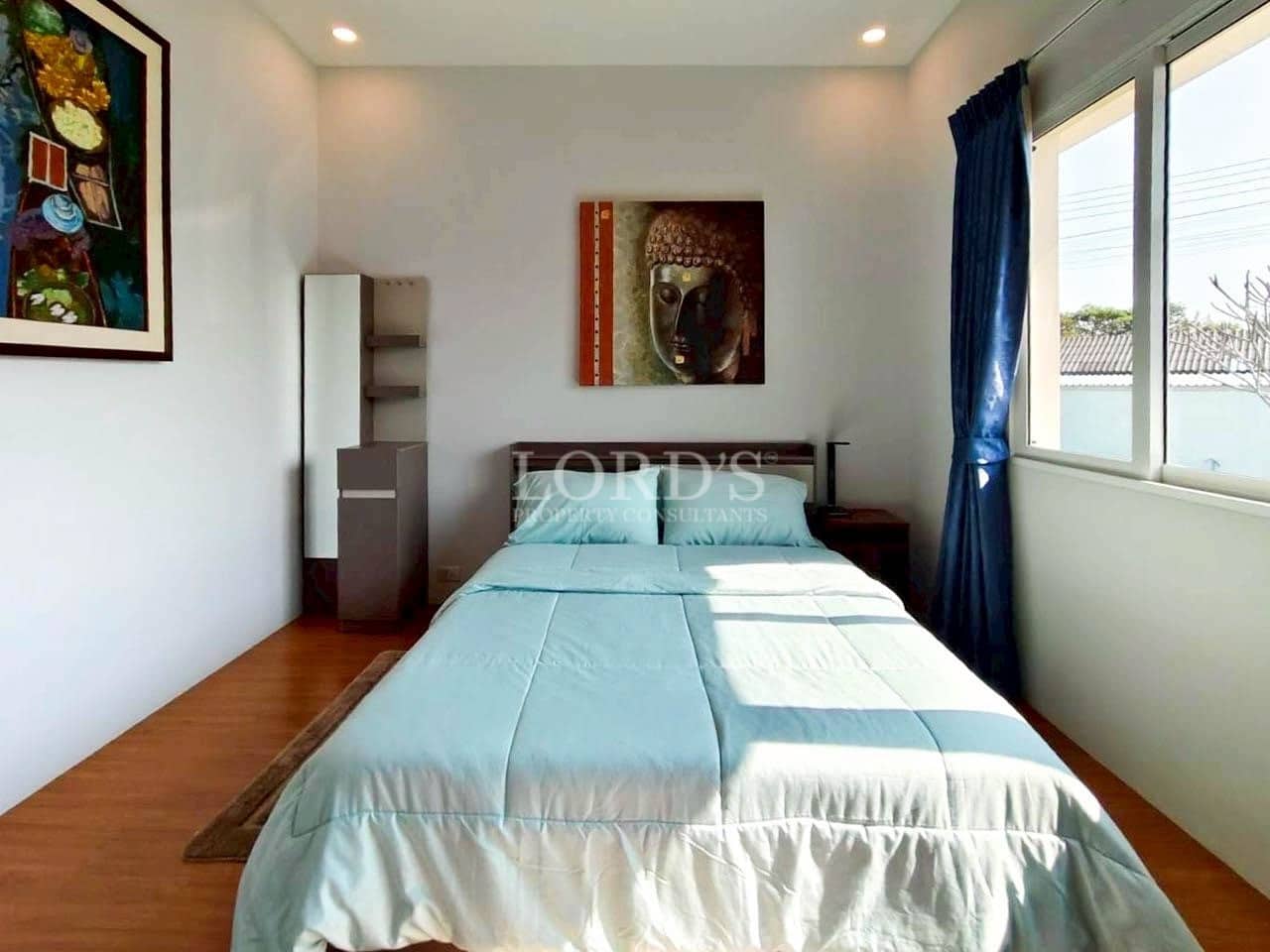 Minimalist bedroom with single bed, Buddha wall art, and natural light.
