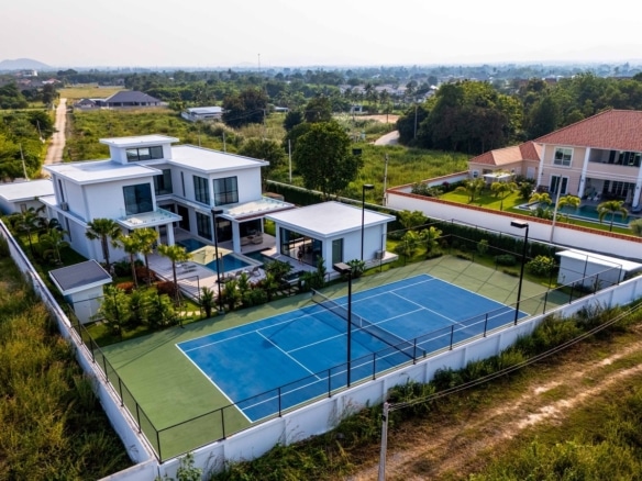 Aerial view of a modern luxury villa with private swimming pool, landscaped garden, and full-size tennis court.