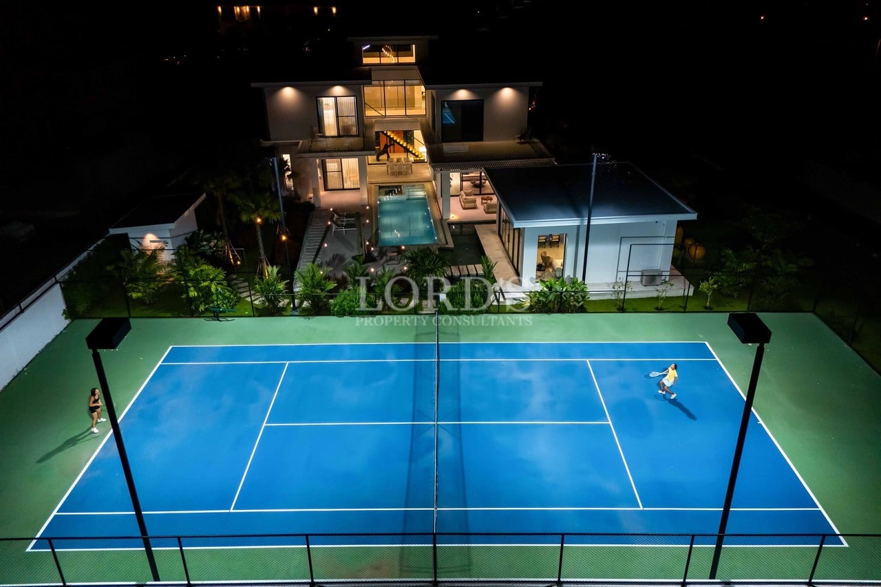 Luxuriöse Villa bei Nacht mit privatem Tennisplatz, Swimmingpool und moderner architektonischer Beleuchtung.