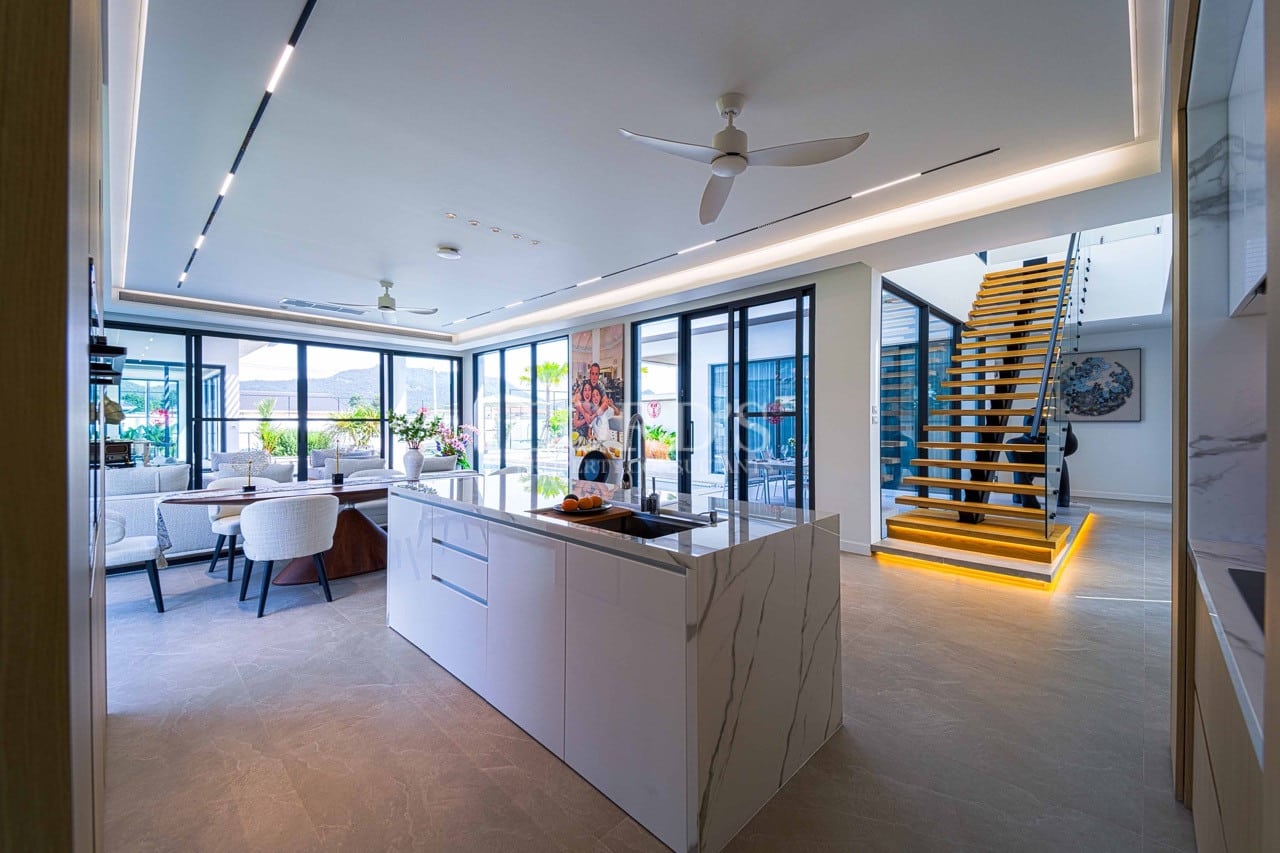 Luxuriöse offene Küche mit Marmorinsel, schwebender Treppe, Glaswänden und eingelassener Deckenbeleuchtung.