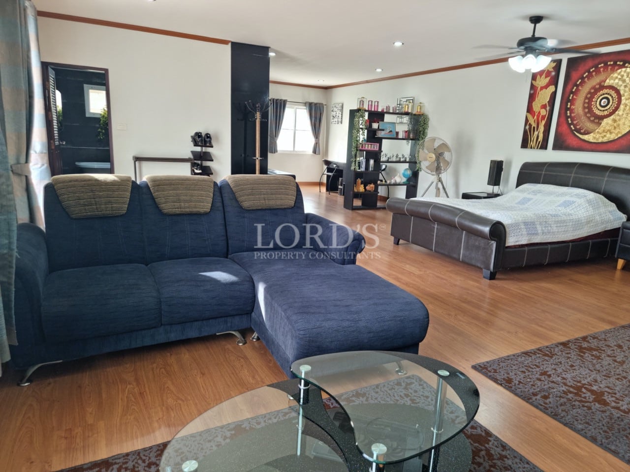 Spacious master bedroom with seating area, wooden flooring, and modern décor.