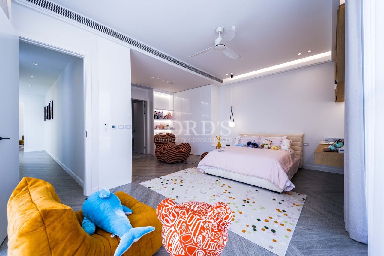 Modernes Kinderzimmer mit zartrosa Bett, verspielten Sitzgelegenheiten, Deckenventilator und eingebauten Regalen.