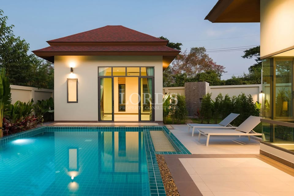 Modern luxury villa with private swimming pool, sun loungers, and garden view at dusk.