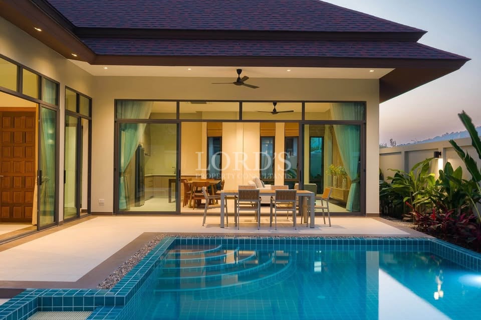 Luxury villa with private swimming pool, covered patio, and glass sliding doors at sunset.
