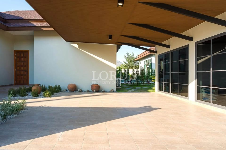 Modern villa outdoor patio with covered terrace, tiled flooring, and large glass sliding doors.