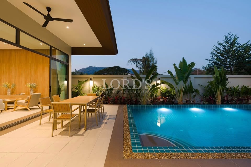 Luxury outdoor dining area beside illuminated swimming pool at modern villa.