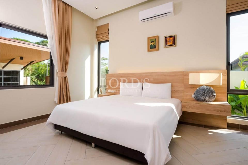 Modern minimalist bedroom with wooden headboard, natural light, and large windows.
