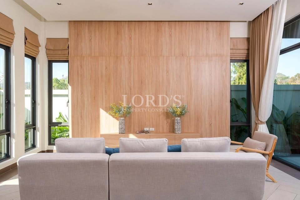 Modern living room with wooden accent wall, sofa seating, and large windows.