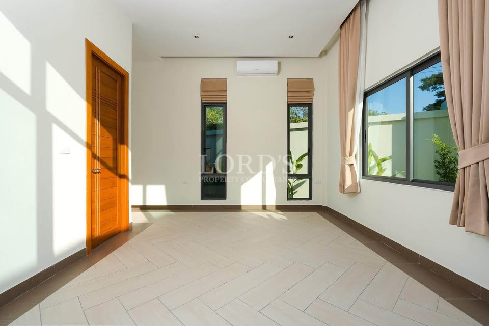 Bright empty bedroom with large windows, tiled floor, and natural sunlight.