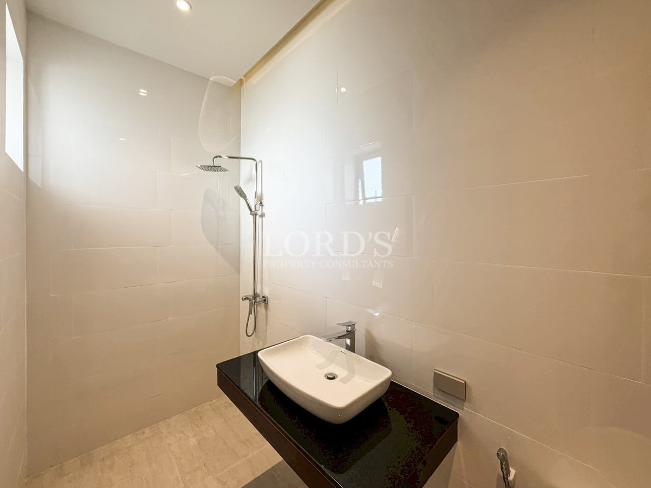 Modern bathroom with walk-in shower, wall-mounted sink, and glossy white tiles.