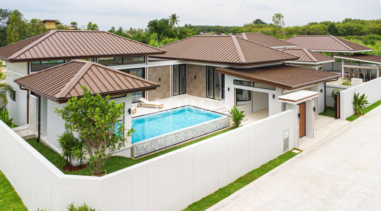 Contemporary luxury villa with private swimming pool, walled garden, and modern roof design.
