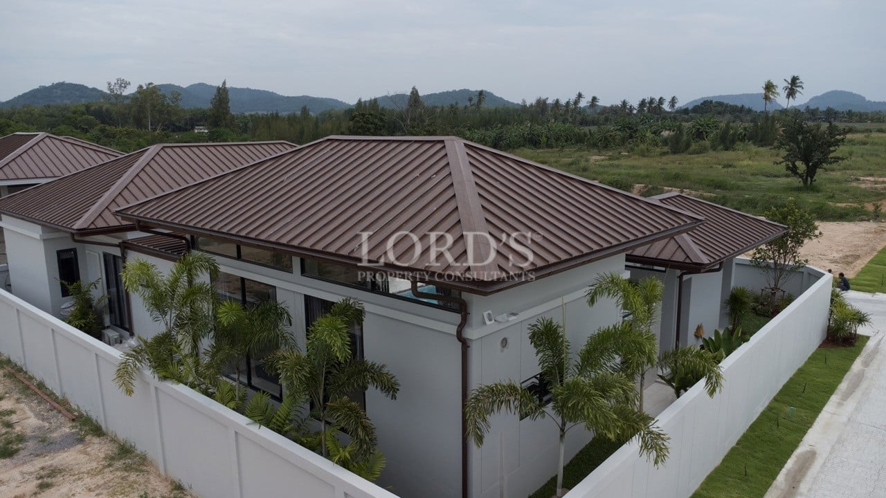 Aerial view of modern single-storey villa with brown metal roof and walled compound
