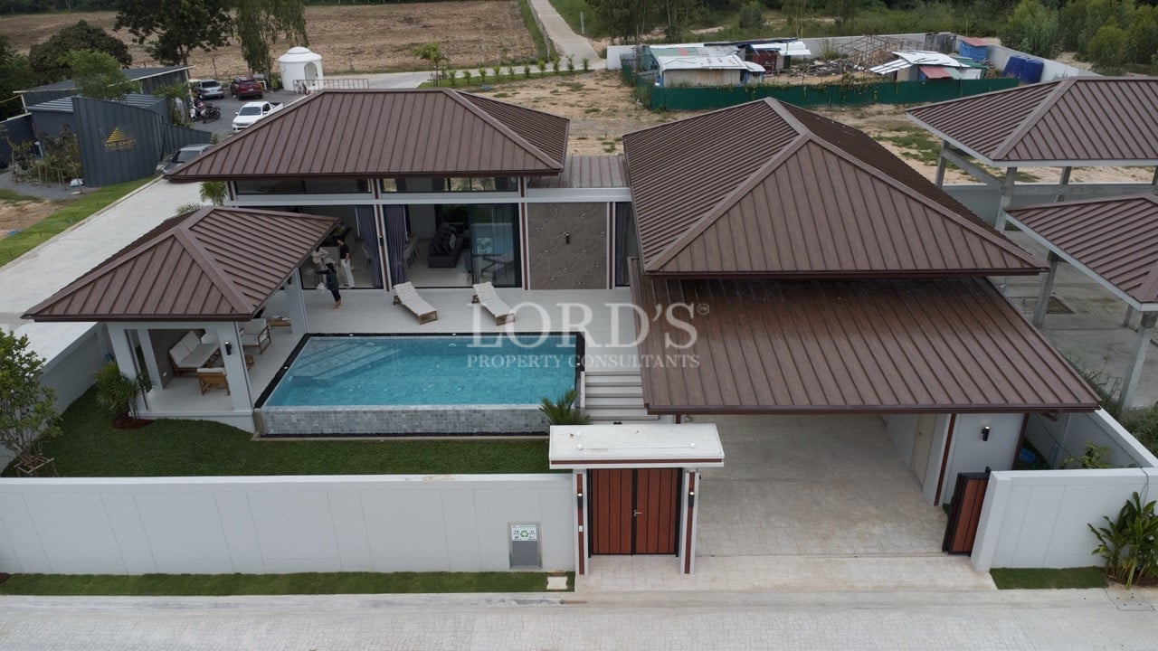 Aerial view of modern villa with private swimming pool, carport, and brown metal roof