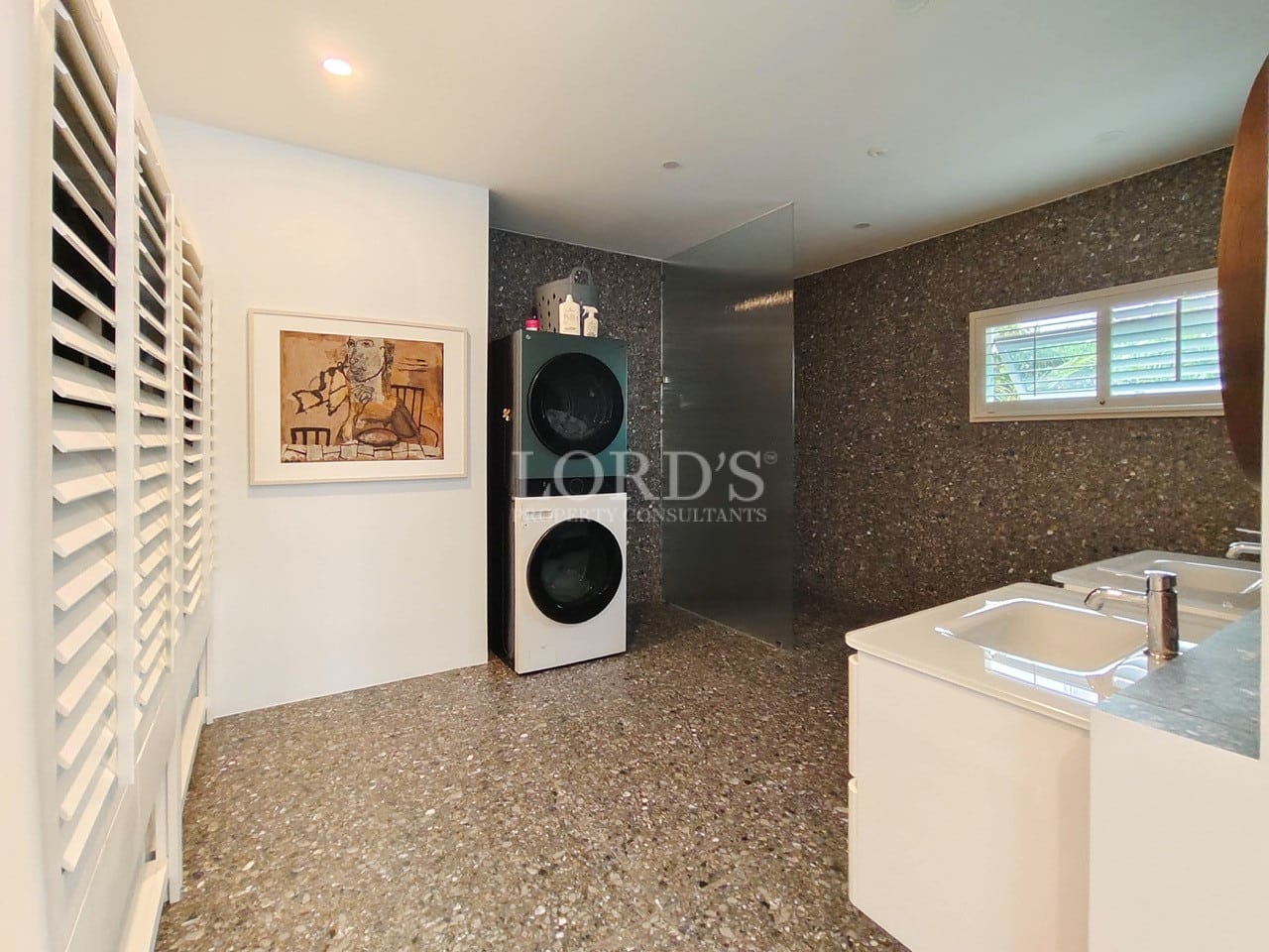 Modern bathroom with walk-in shower, double vanity, and integrated washer and dryer.