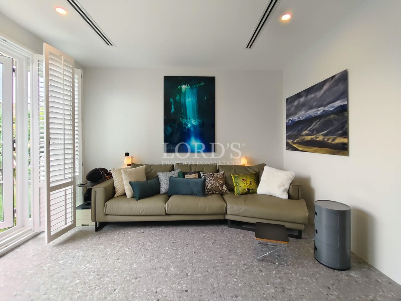 Modern seating area with sectional sofa, accent cushions, contemporary artwork, and natural light.