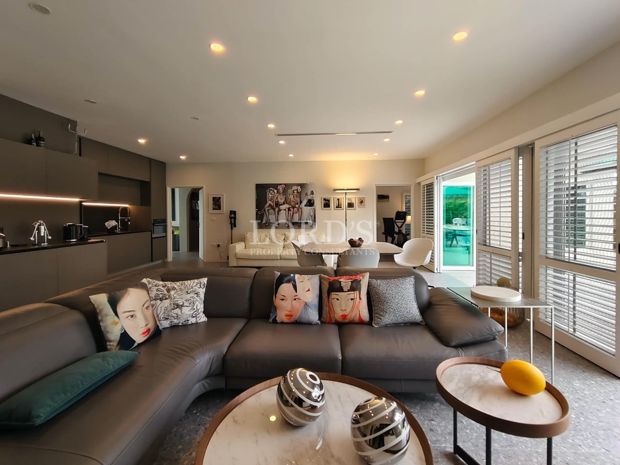 Open-plan living room with modern sectional sofa, contemporary décor, and integrated kitchen.