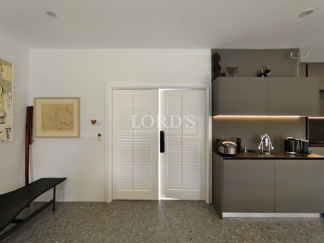 Modern interior with minimalist bench seating, contemporary artwork, and sleek kitchen cabinetry.