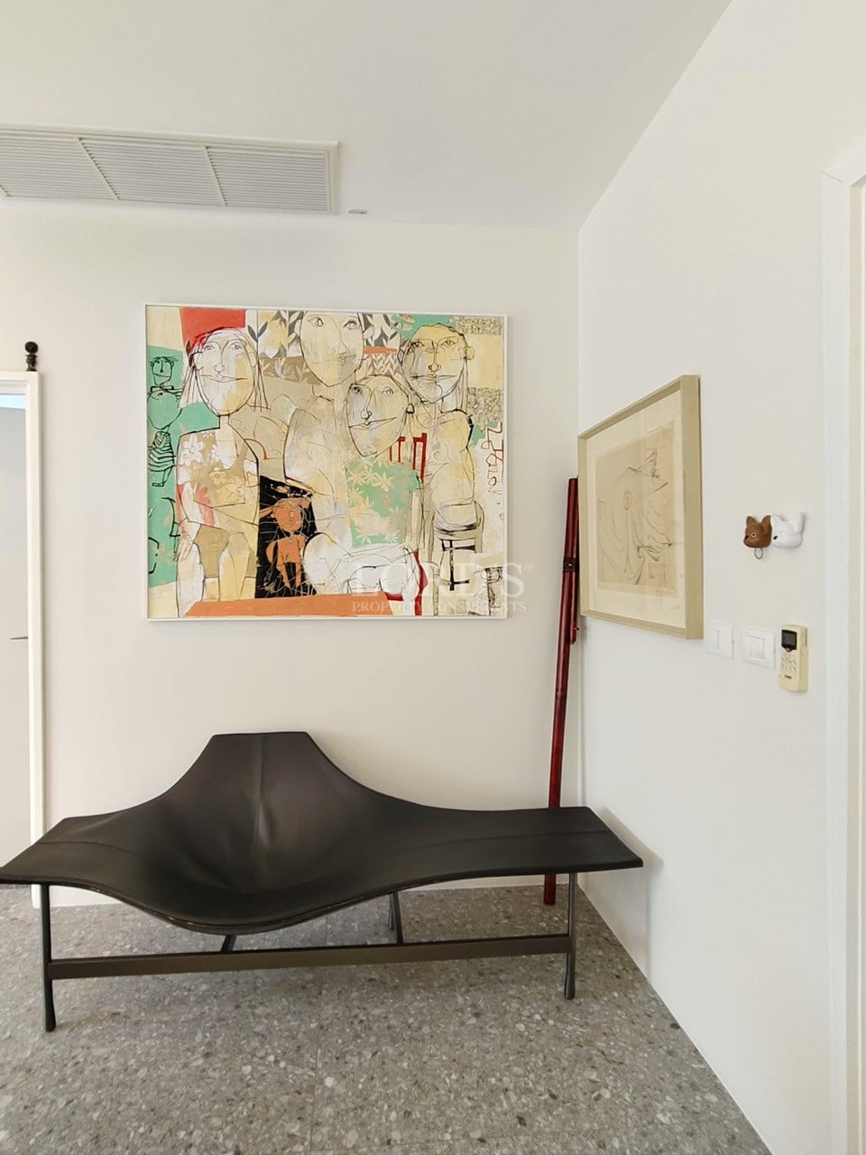 Modern interior seating area with sculptural bench and contemporary artwork on white walls.