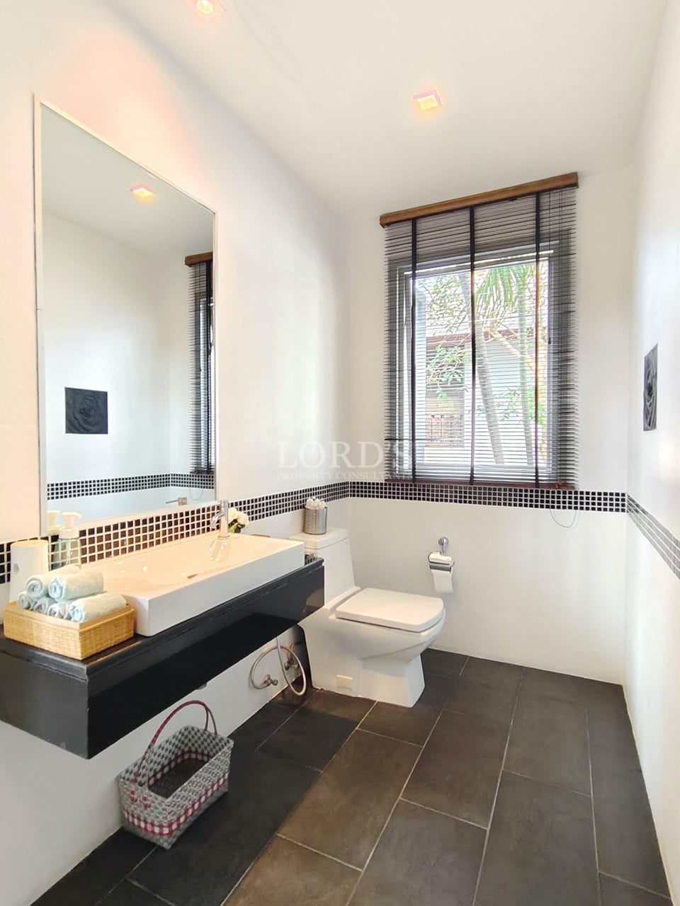 Modern guest bathroom with floating vanity, large mirror, and window light.