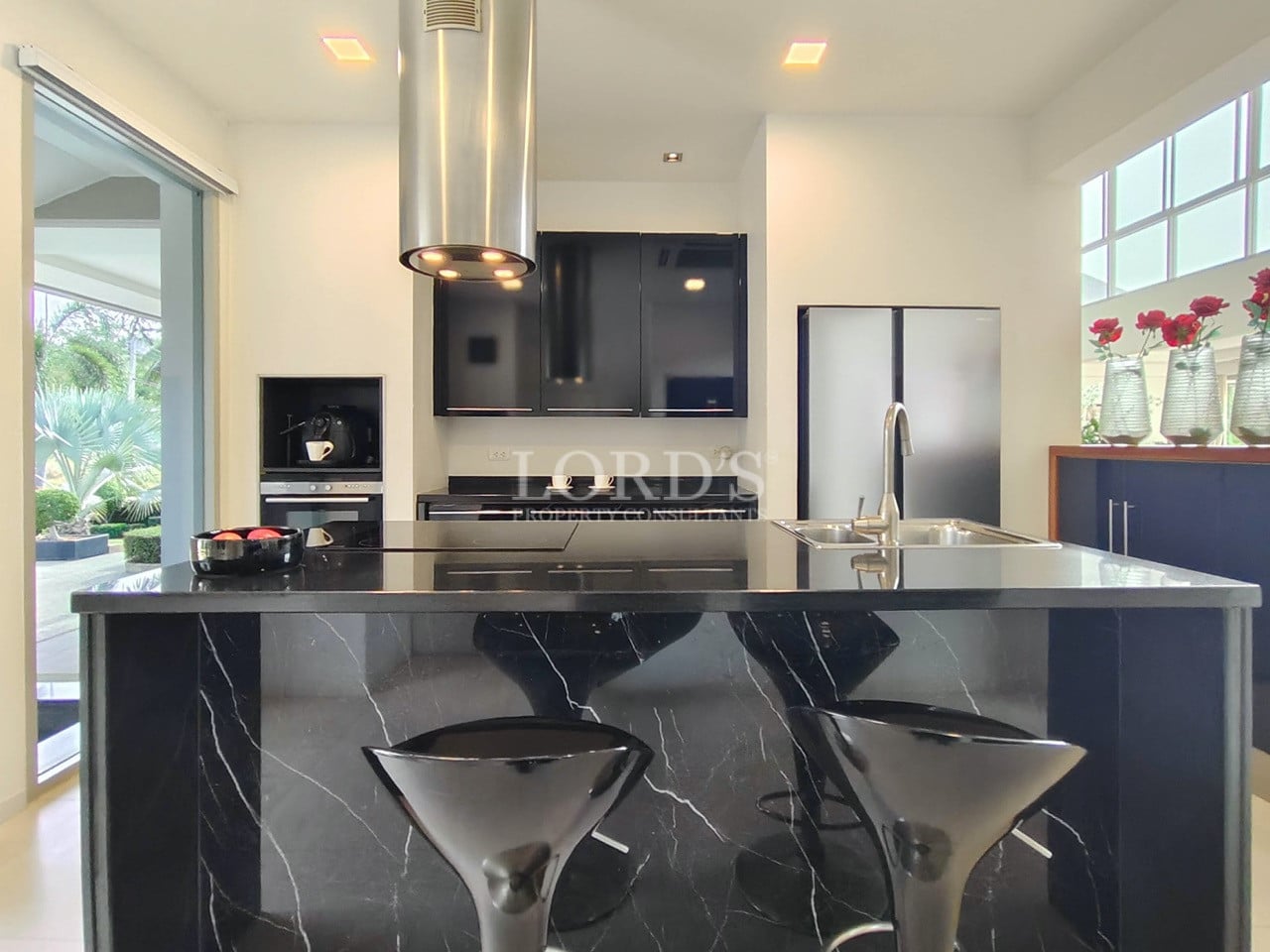 Modern kitchen with black marble island, bar stools, and built-in appliances.