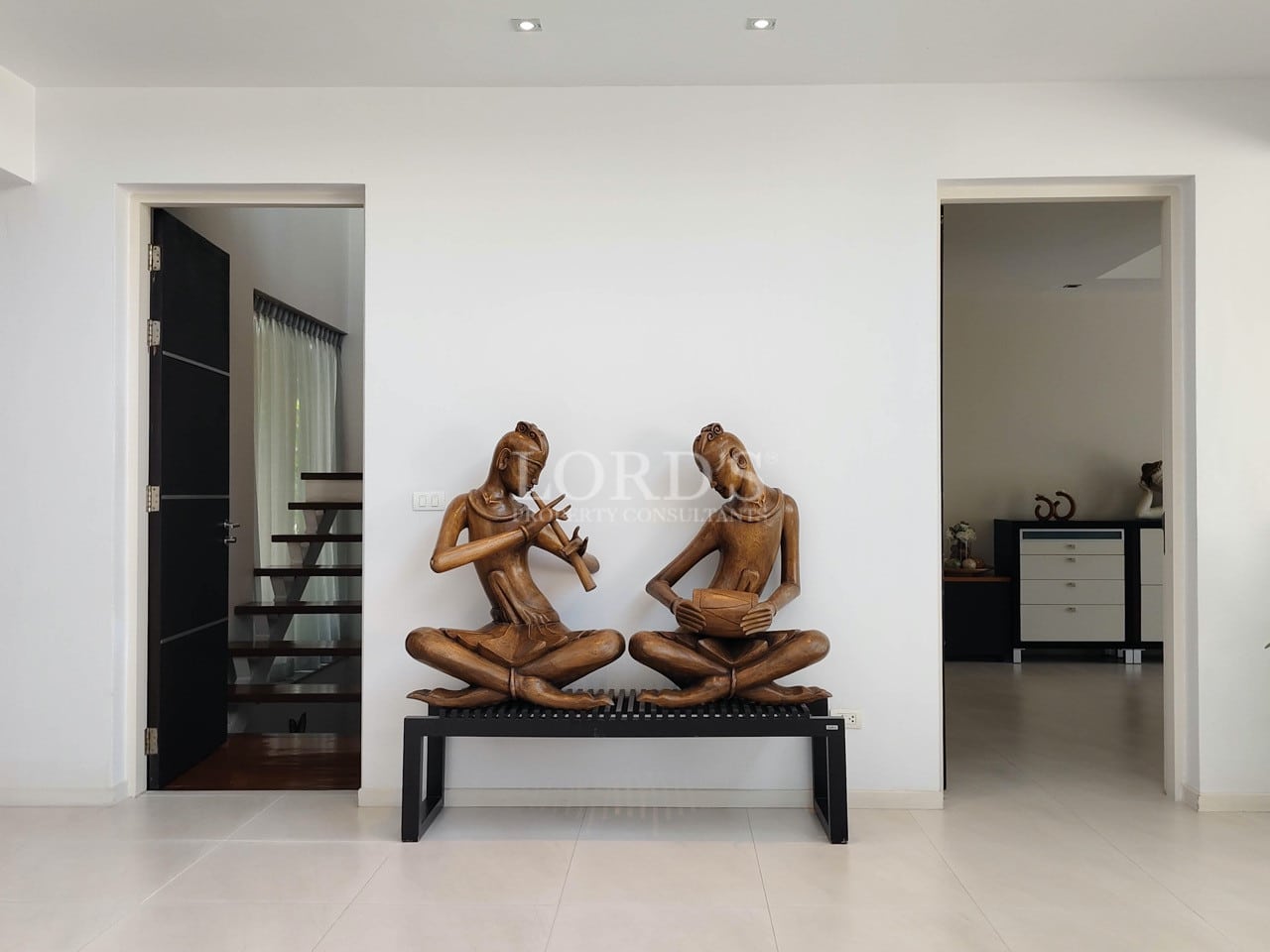 Modern villa interior with decorative wooden sculptures and minimalist hallway design.