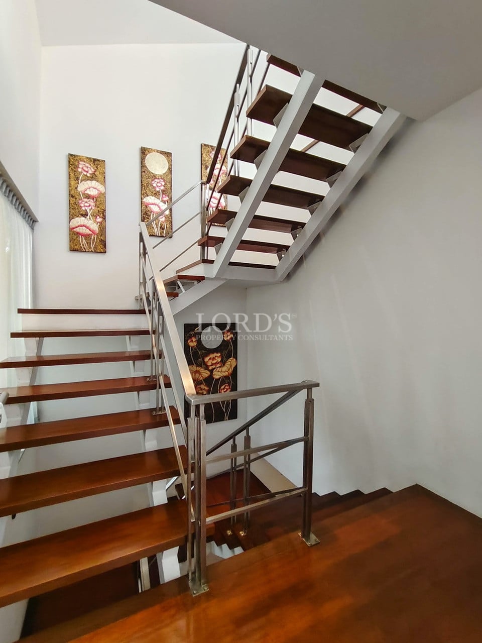 Modern villa staircase with wooden steps, metal railings, and artistic wall décor.