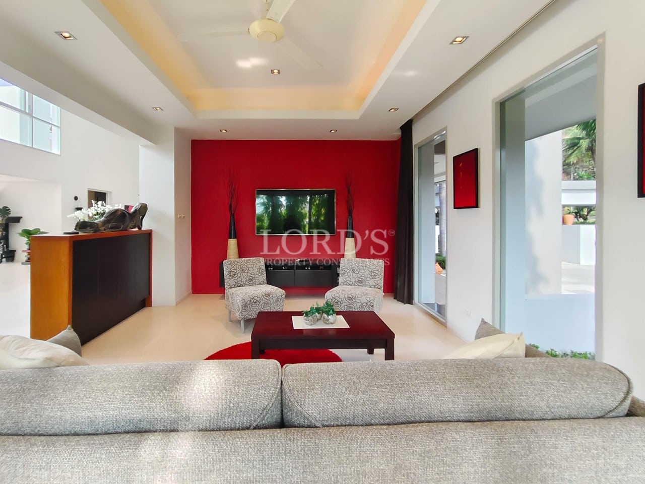 Modern luxury villa living room with red accent wall and stylish seating.