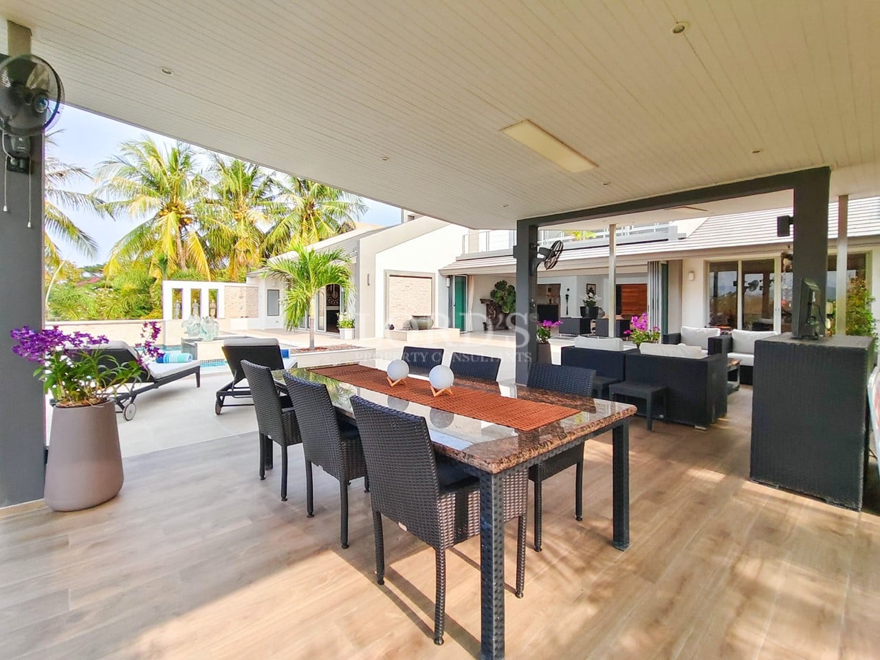 Luxury villa outdoor dining and lounge area overlooking the pool and tropical garden.