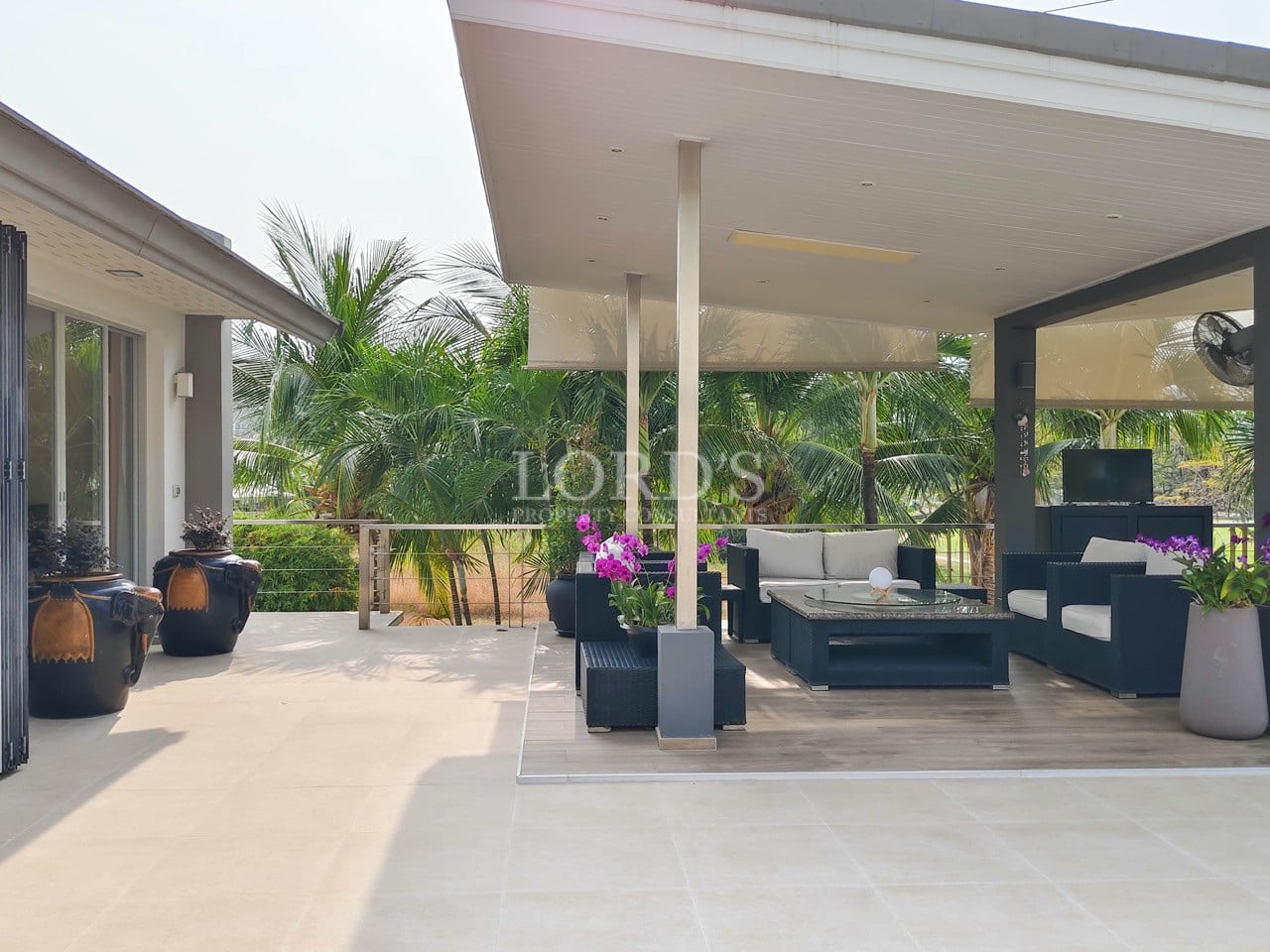 Luxury villa outdoor lounge with covered terrace and tropical garden views.
