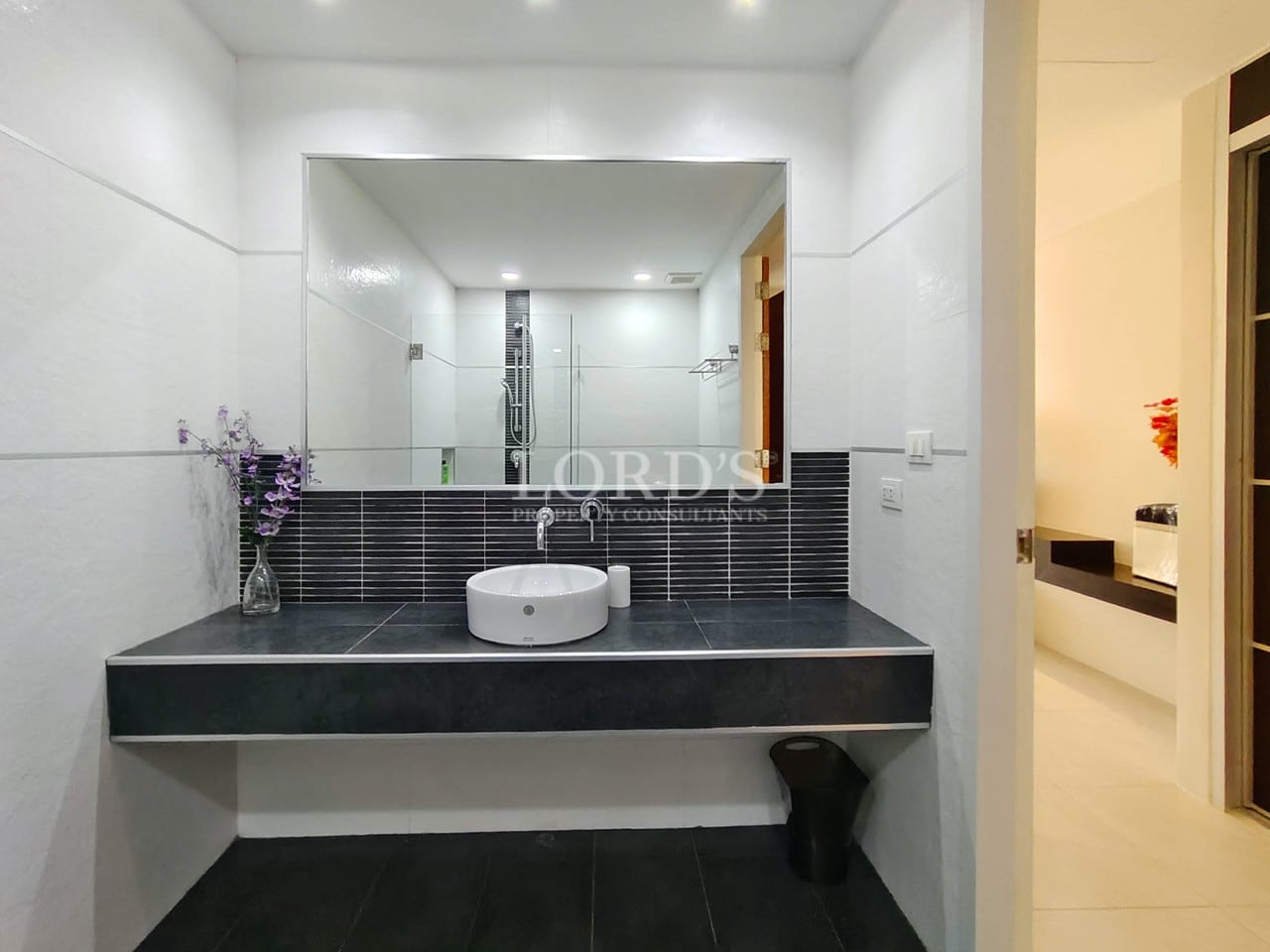 Modern villa bathroom vanity with countertop basin and large wall mirror.