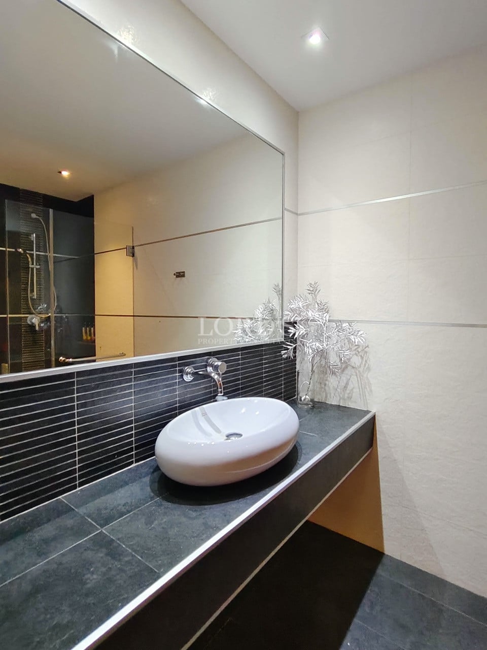 Modern villa bathroom vanity with countertop sink and large mirror.
