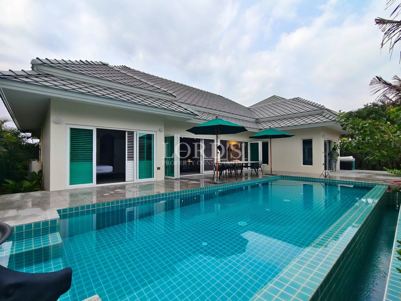 Modern single-story pool villa with private swimming pool, tiled roof, and outdoor patio seating