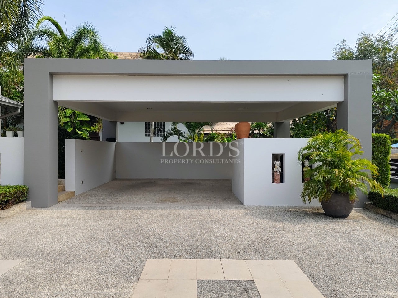Modern villa covered carport with minimalist design and landscaped greenery.