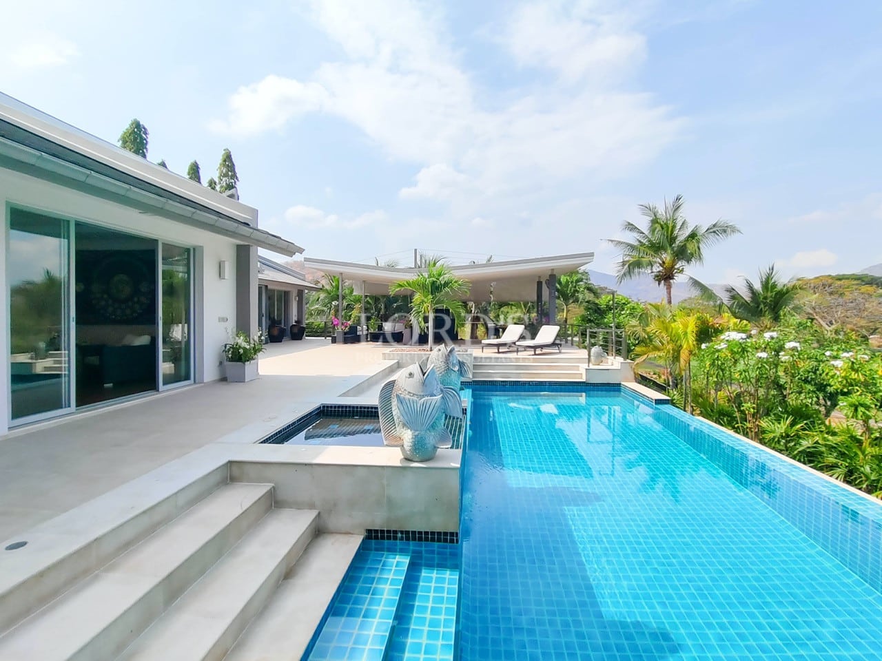 Luxury villa swimming pool with sun deck and tropical garden views.