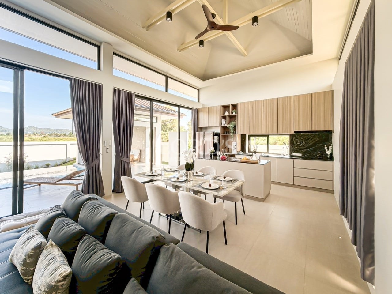 Open-plan dining and kitchen area with high ceiling, large windows, and modern furniture