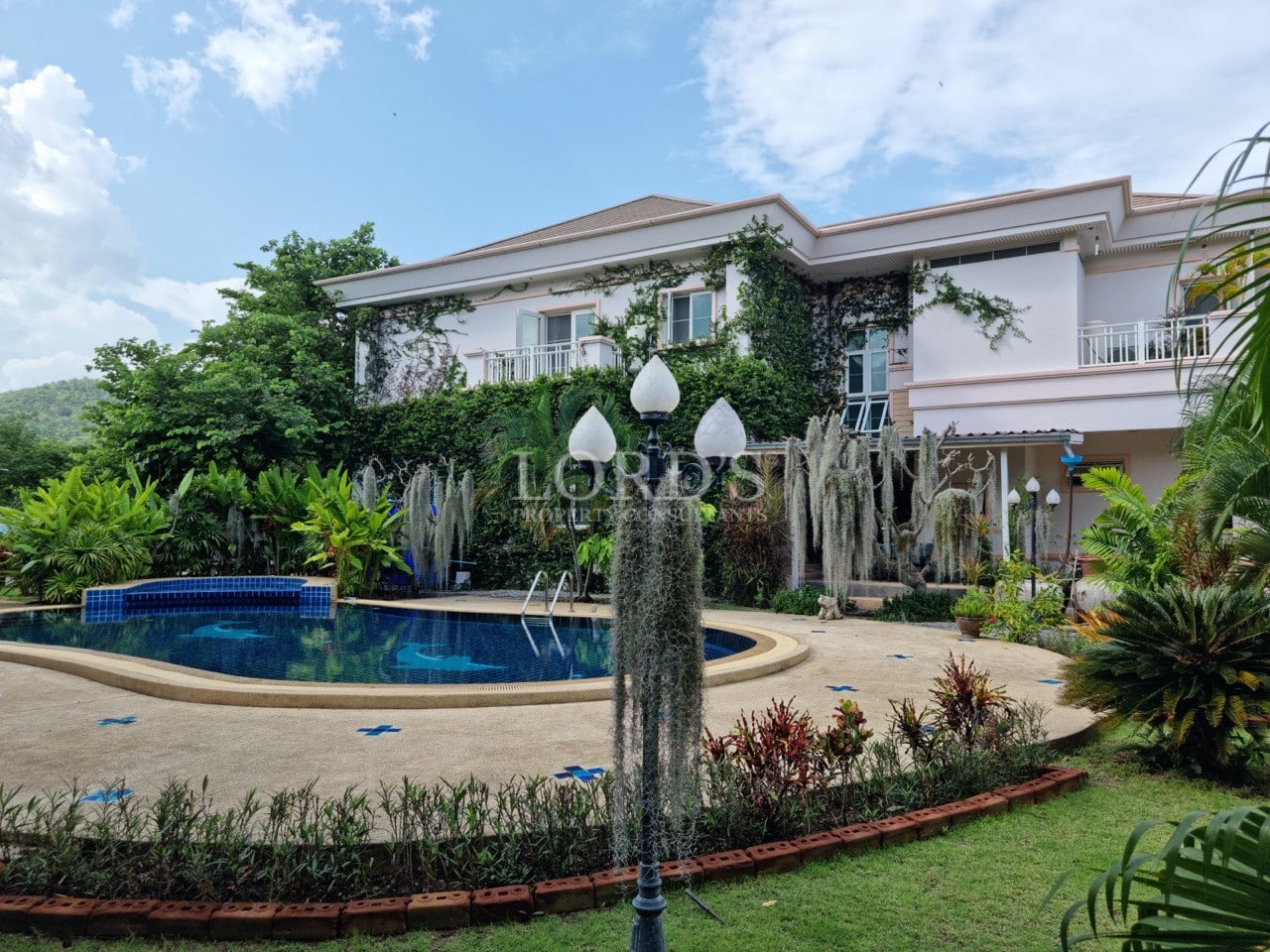 Luxury villa with private swimming pool, landscaped garden, and ivy-covered exterior.