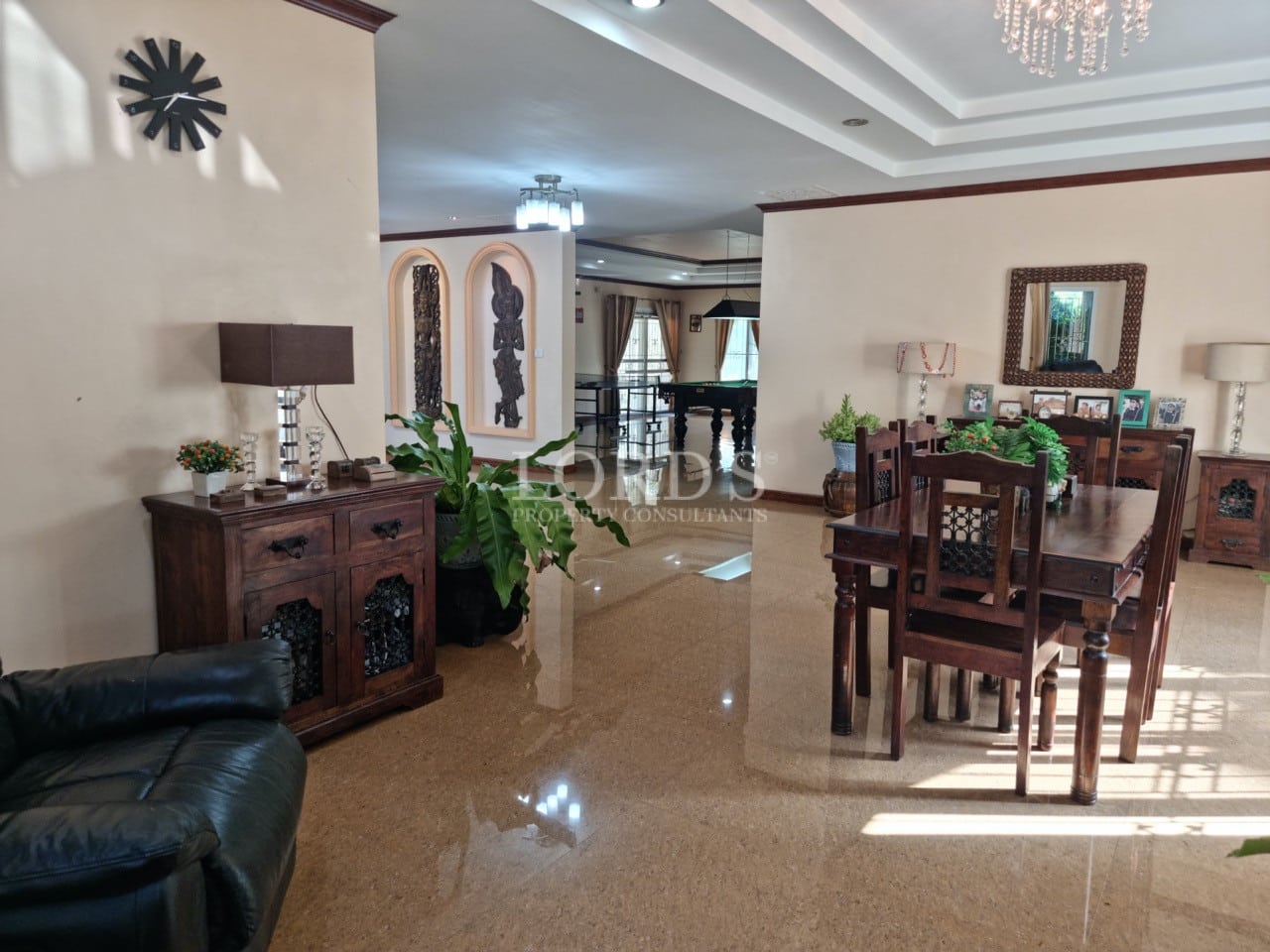 Modern villa with a covered carport and wide concrete driveway surrounded by tropical landscaping.