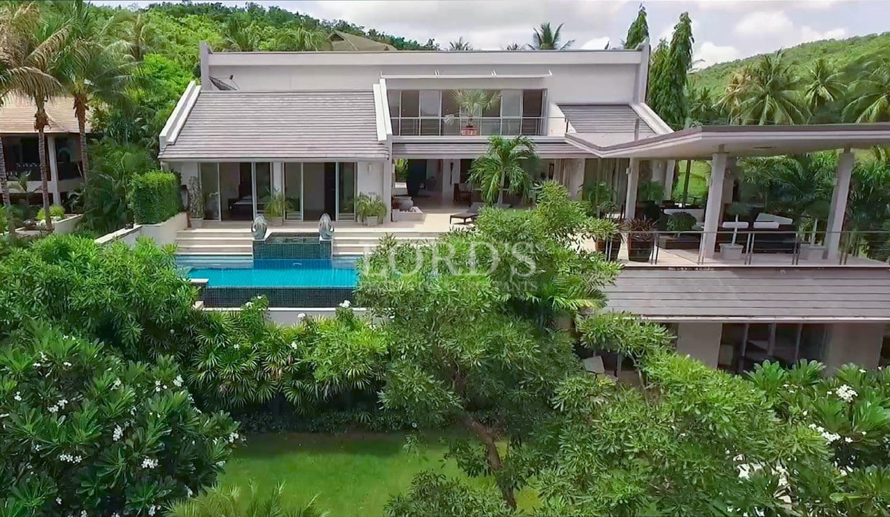 Front view of a modern luxury villa with a private infinity pool surrounded by tropical greenery.