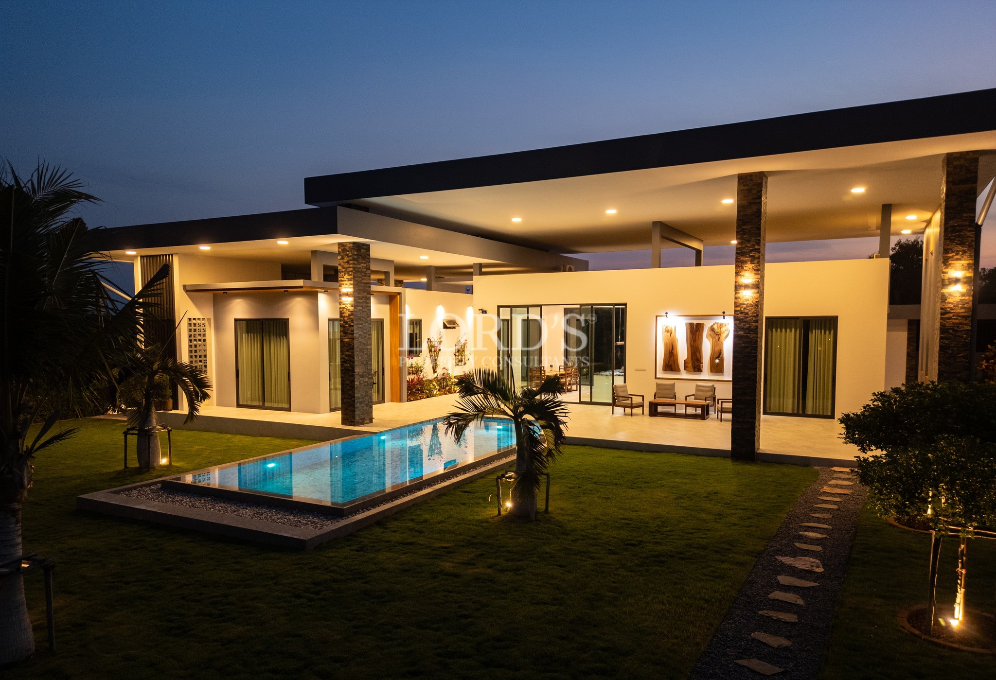 Modern luxury villa at night with illuminated swimming pool and outdoor lighting.