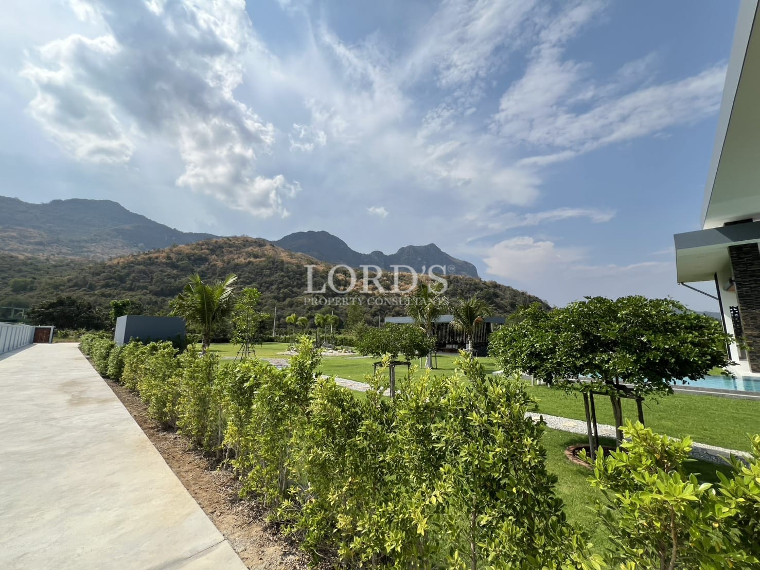 Landscaped garden pathway with trimmed hedges and mountain views.