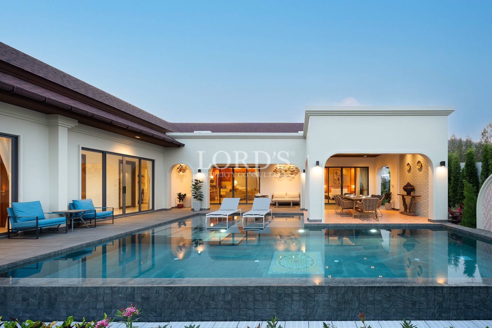Luxury villa with private swimming pool, outdoor lounge seating, and covered dining terrace at dusk.
