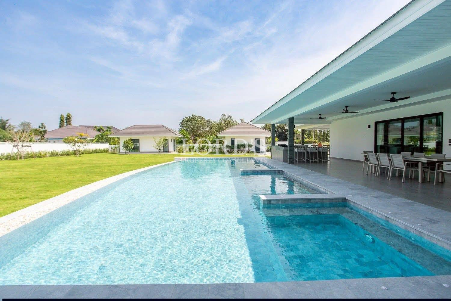 Modern luxury villa with large private swimming pool, garden lawn, and covered outdoor dining area