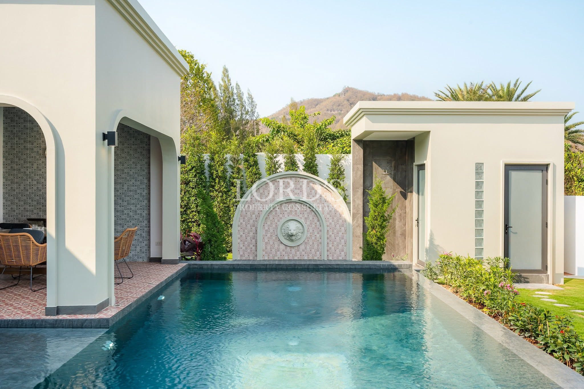 Private villa swimming pool with decorative water feature and landscaped garden surroundings.