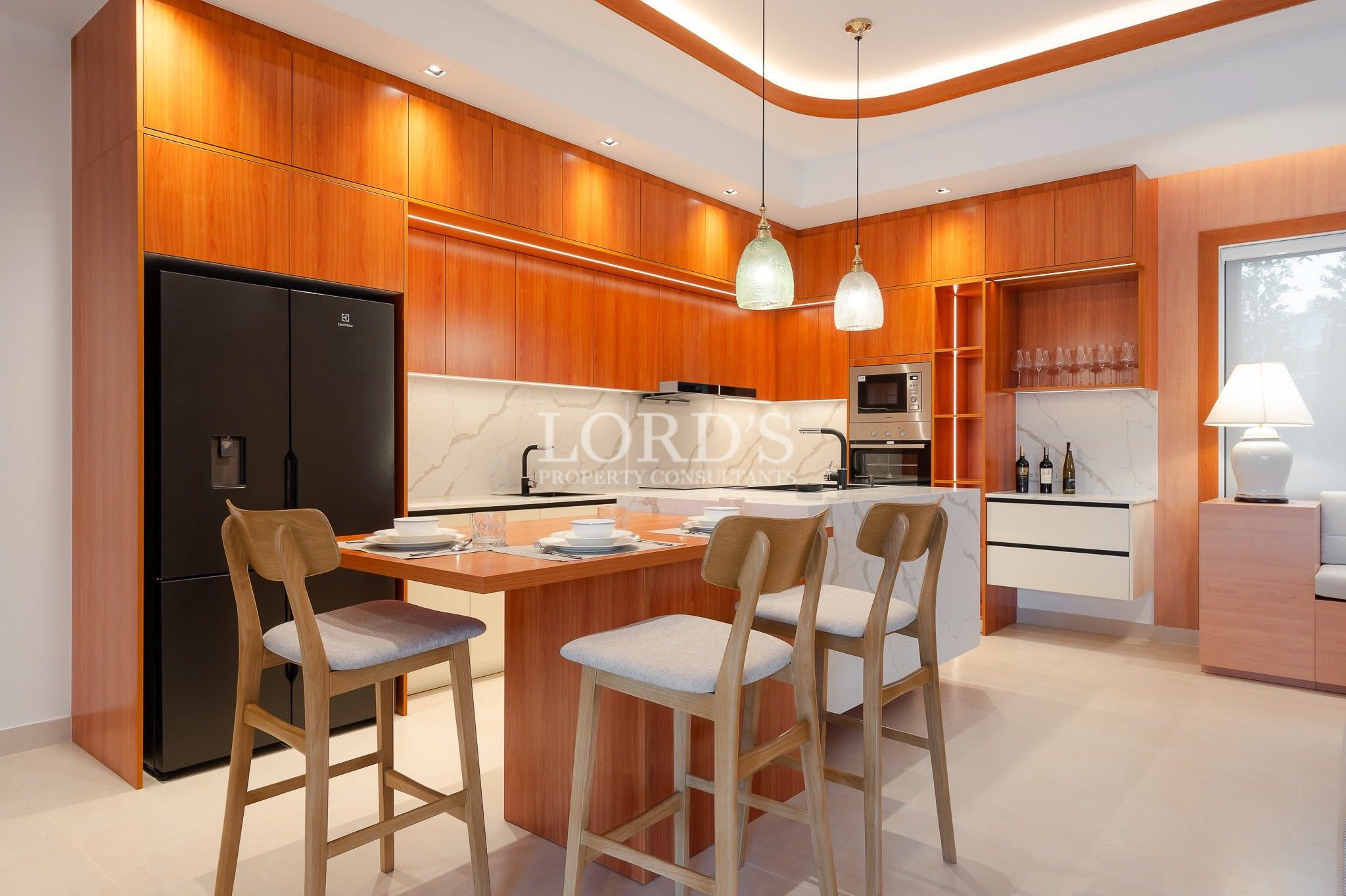 Modern kitchen with wooden cabinetry, breakfast island, and pendant lighting.