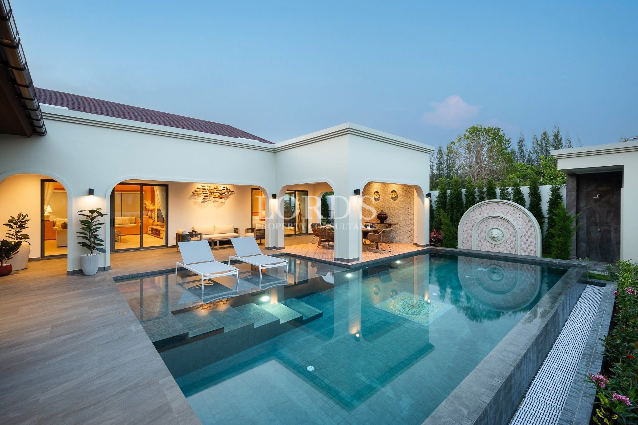 Luxury villa courtyard with private swimming pool, sun loungers, and covered outdoor living areas.