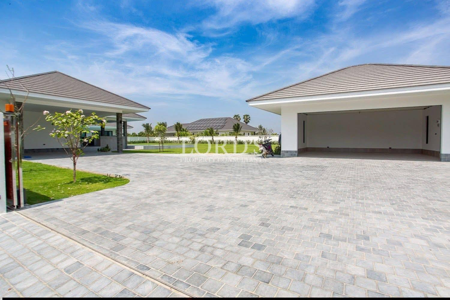 Modern home driveway with large paved courtyard and two covered garage spaces.