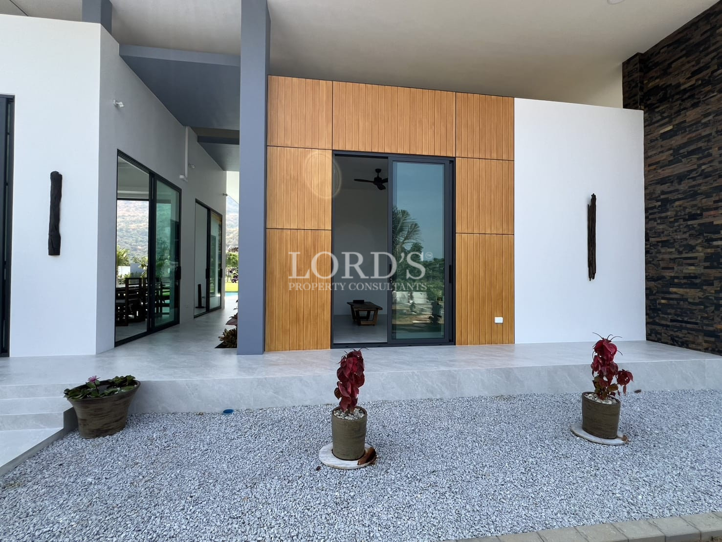 Modern villa exterior entrance with wood panel façade and sliding glass doors.